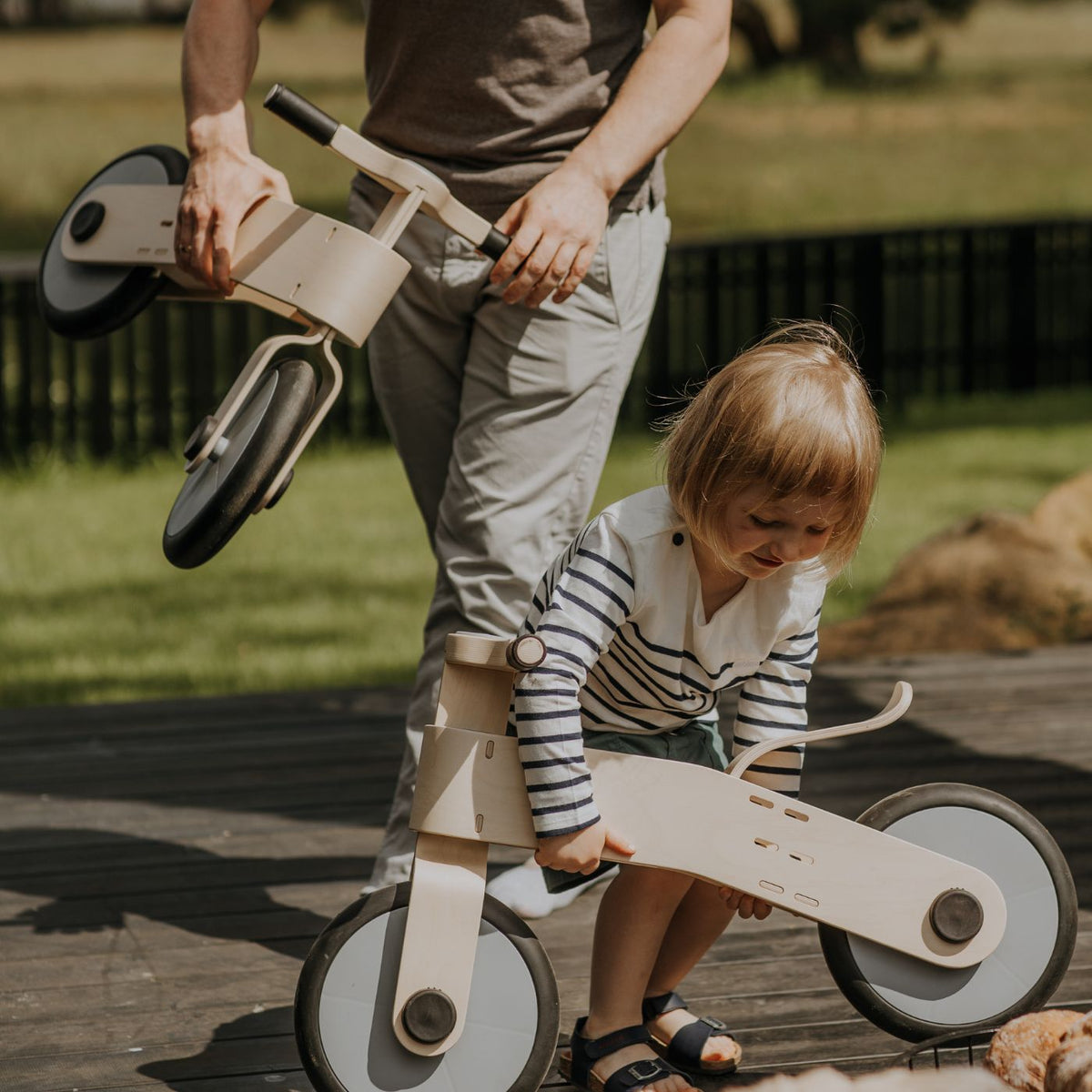 2 year old toddler riding a wooden balance bike outdoors